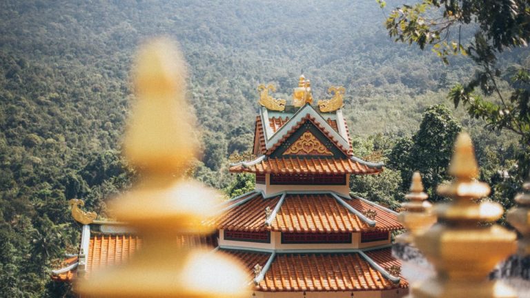 Beautiful temple architecture nestled in a lush, mountainous setting on a sunny day.